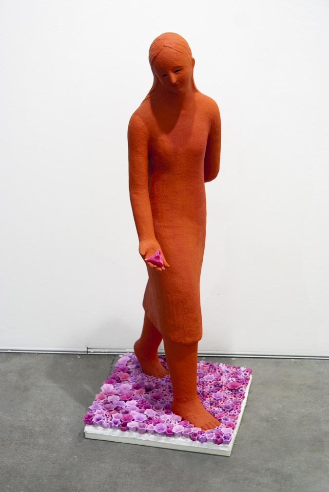 Girl walking on the flower 2006, Sculpture by Kazumasa Mizokami, A red statue of a young woman trying to sprinkle a flower on her right hand, underneath her are many pink flowers.