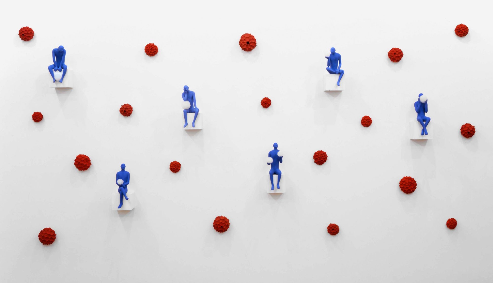 An installation Set up Blue men by Kazumasa Mizokami at the Toselli Gallery in 1995 in Milan. that uses six small blue statues set up on the wall and open space is accompanied by 18 red flower photo by Stefano Cavallo