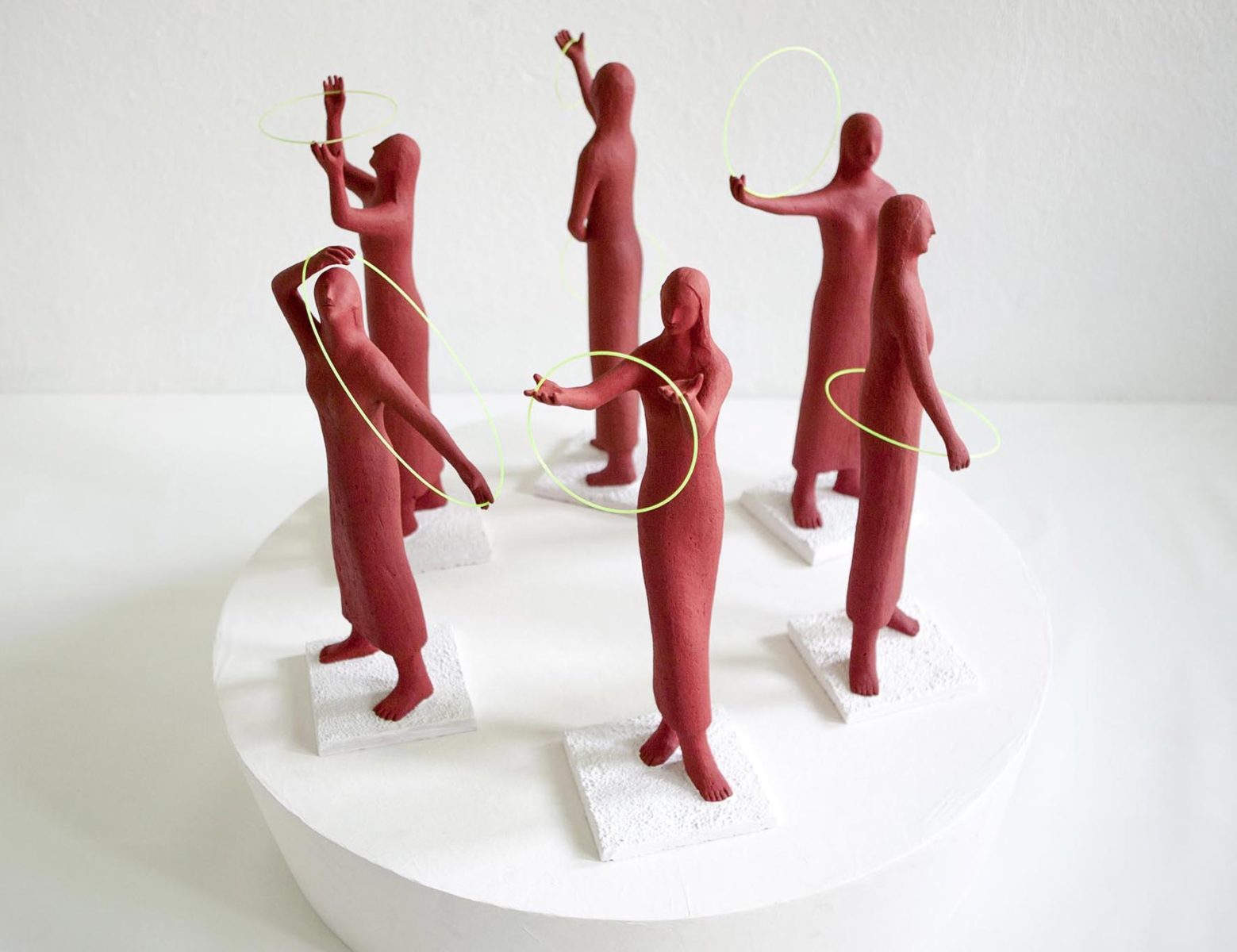 The composition of red women 2004, Sculpture by Kazumasa Mizokami, Six red female statues forming a circle, dancing with a thin yellow hoop.