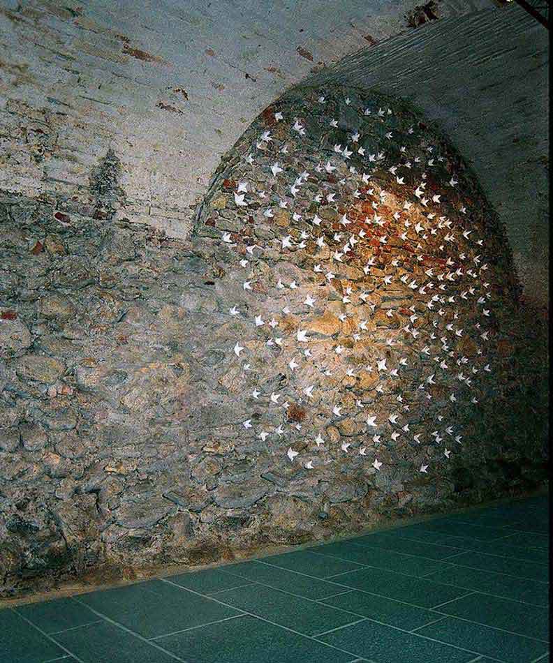 installation by Kazumasa Mizokami 2004, using white flowers on another wall from the previous exhibition Old church. The walls are made of small rocks and white flowers are placed in the crevices to reveal a round white space.