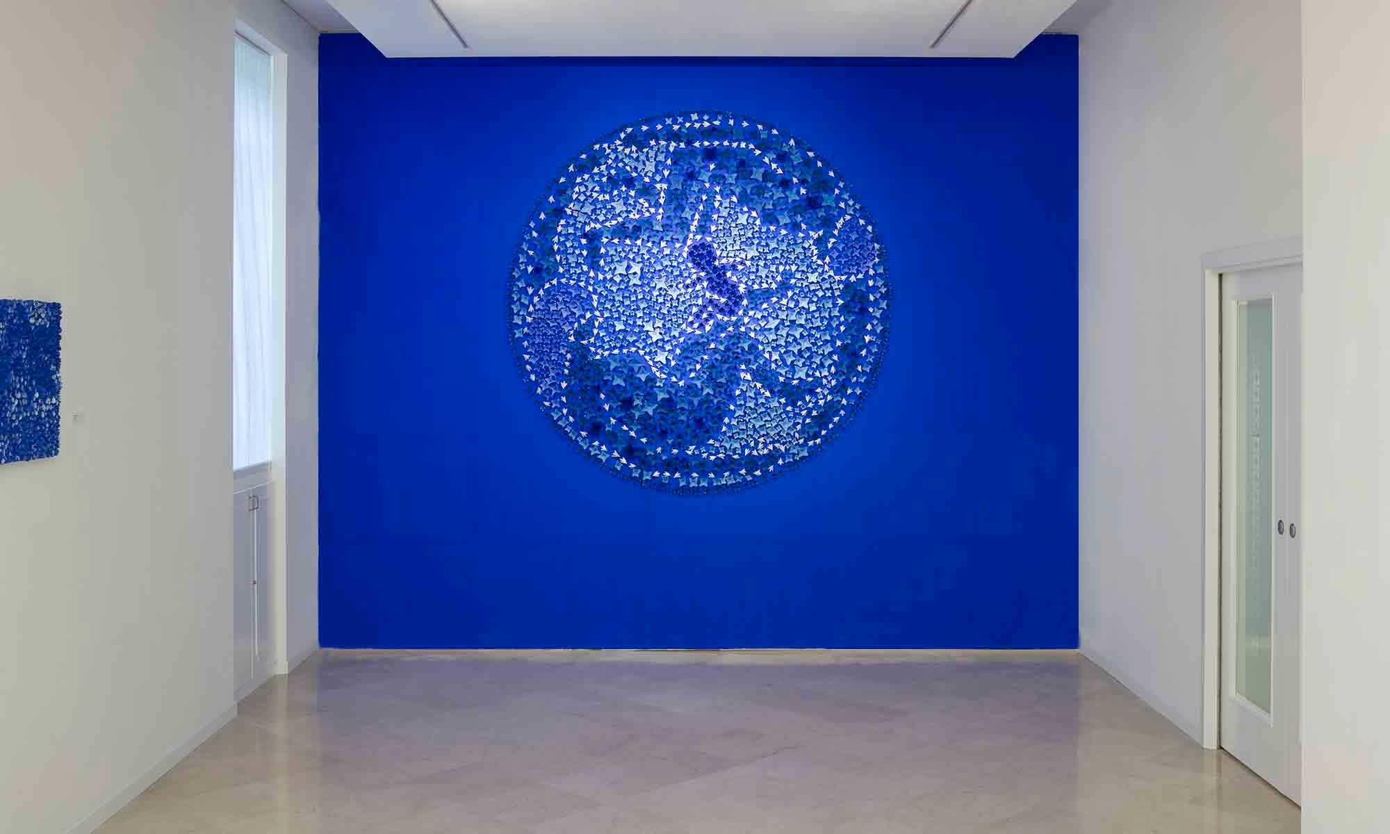 exhibitions of gallery l’incontro Installation by Kazumasa Mizokami 2010 The deep inner wall is deep blue in color. In addition, a large number of small blue and white terracotta flowers are applied and fixed the shapes of men and women in a round shape, in the center a small child, one sees a large installation of earth. 