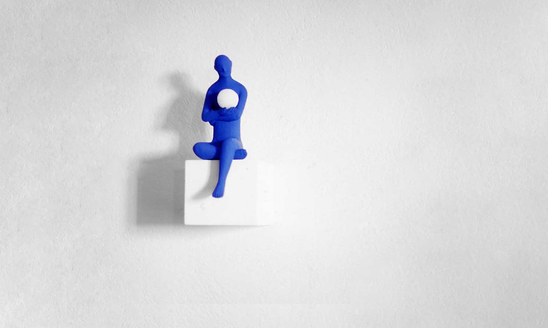 Blue men 1998, Sculpture of Kazumasa Mizokami, A large white wall with a human figure painted blue holding a white sphere in his arms