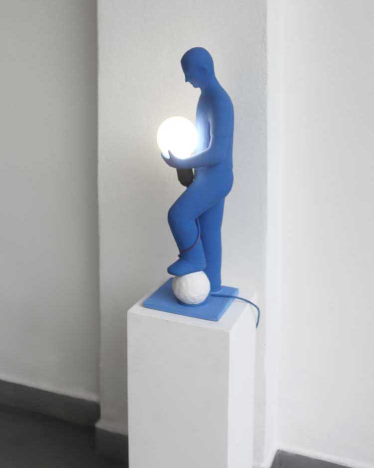 The sense of gravity 2007-2020 62x18x18cm painted terracotta A blue boy statue made by kazumasa, holding a white soul with his left foot and holding a white light bulb with his left hand
