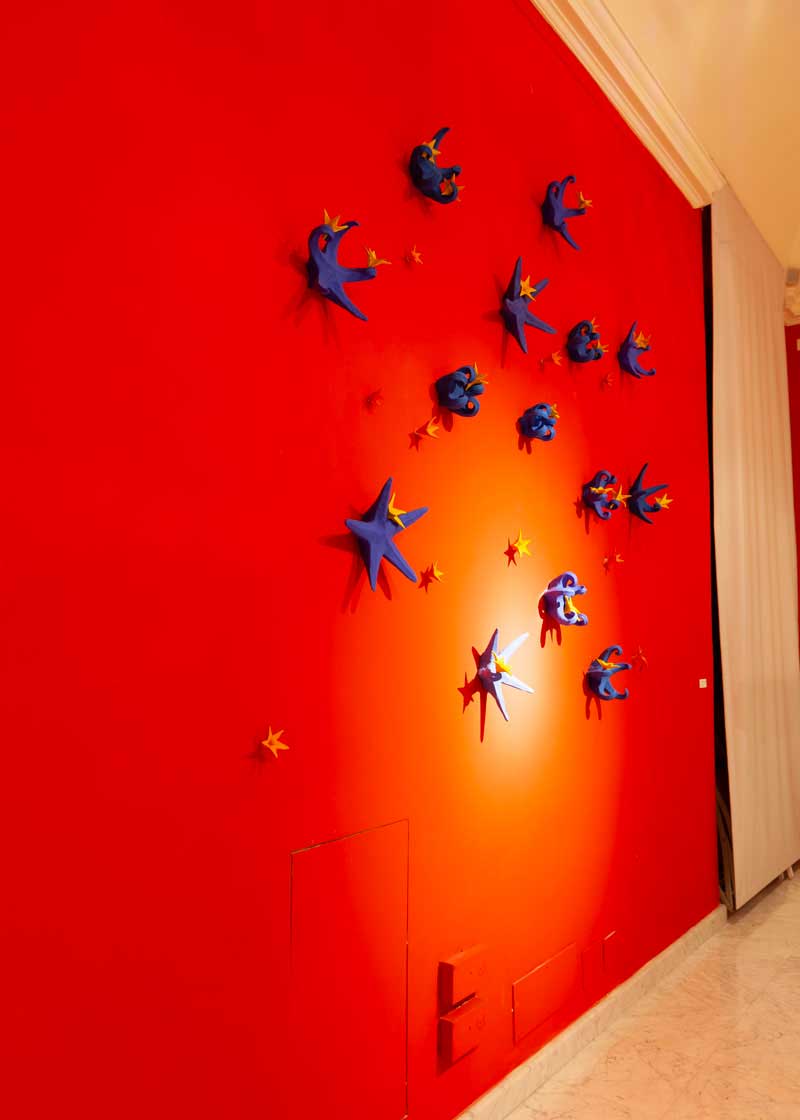 Exhibition set-up and the work 'The Natte dancing with the stars' at the bottom of the red wall a composition of 14 blue and yellow star pieces Made by Kazumasa Mizokami