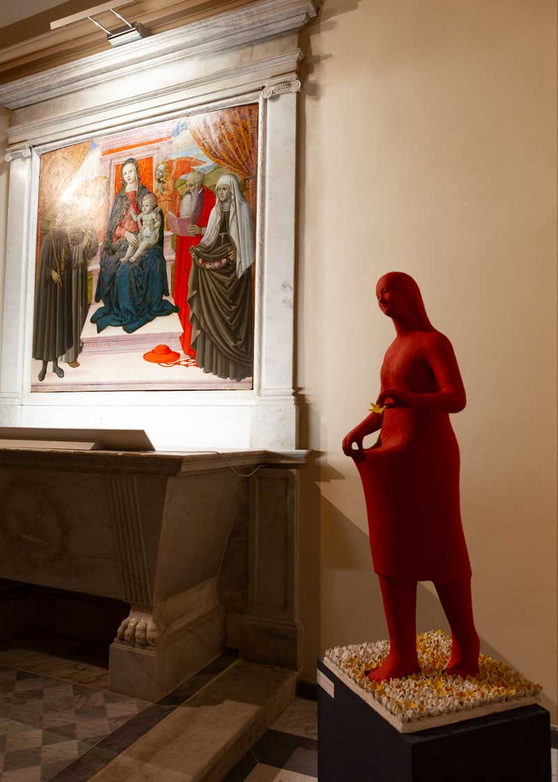 Exhibition set-up the work made by Kazumasa Mizokami a statue of a red girl carrying a yellow flower painted terracotta