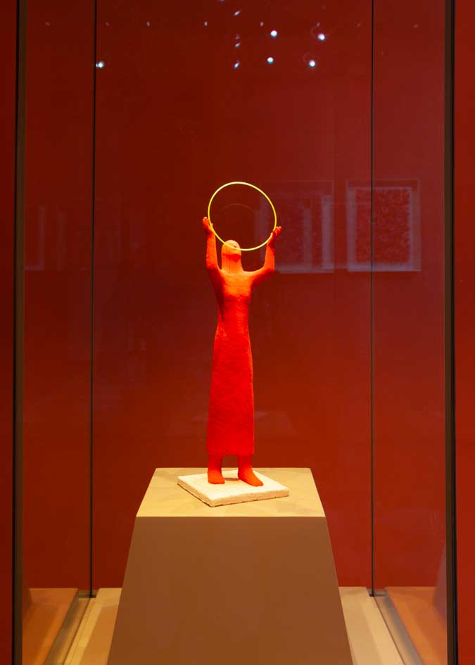 Exhibition set-up in made by Kazumasa Mizokami the red female figure statue holding up a yellow circle