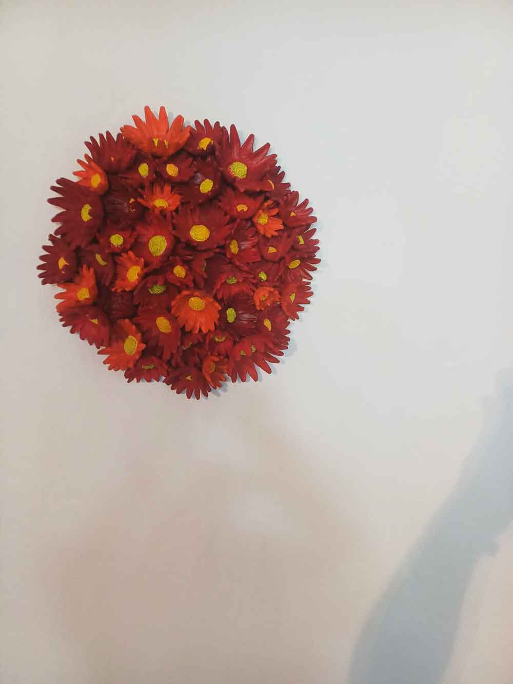 the work in the exhibition, many shapes such as the Tolippani flower attached to a round base made of terracotta and then colored in various reds made by Kazumasa Mizokami